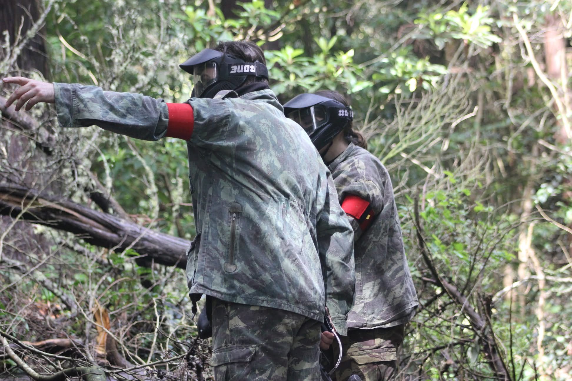 Dois jogadores a combinar estratégia durante o jogo de paintball
